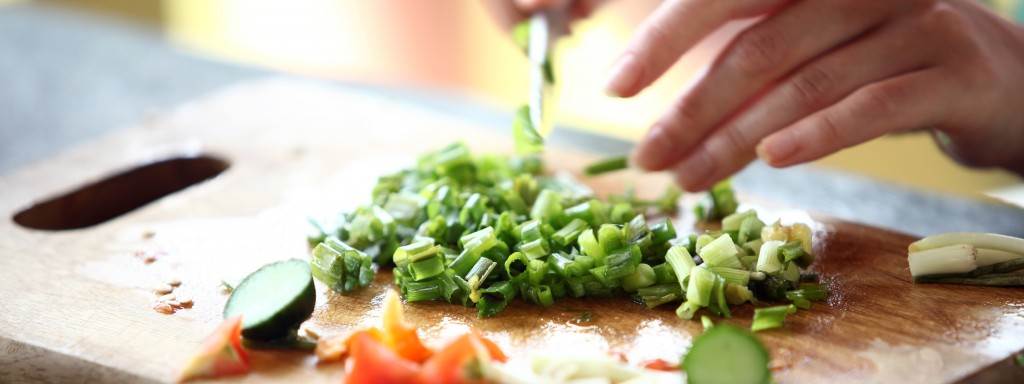 a woman chops zucchini on a cutting board.